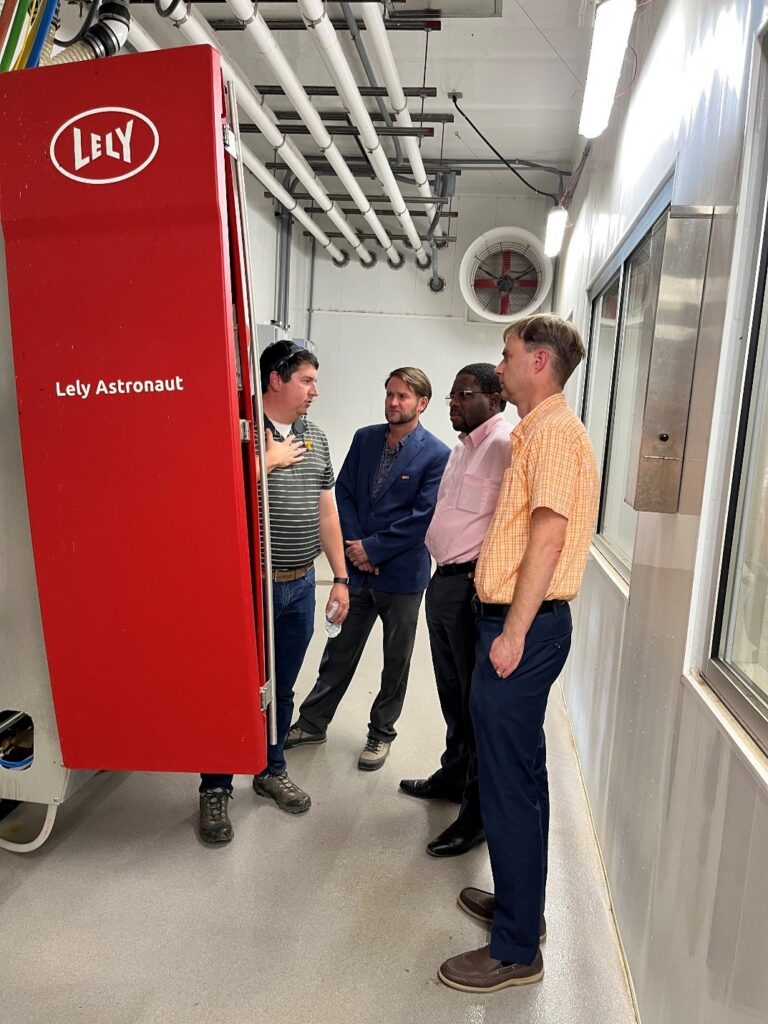 Station personnel and faculty discussing the new Robotic Milker machine at the Little River Dairy Unit.